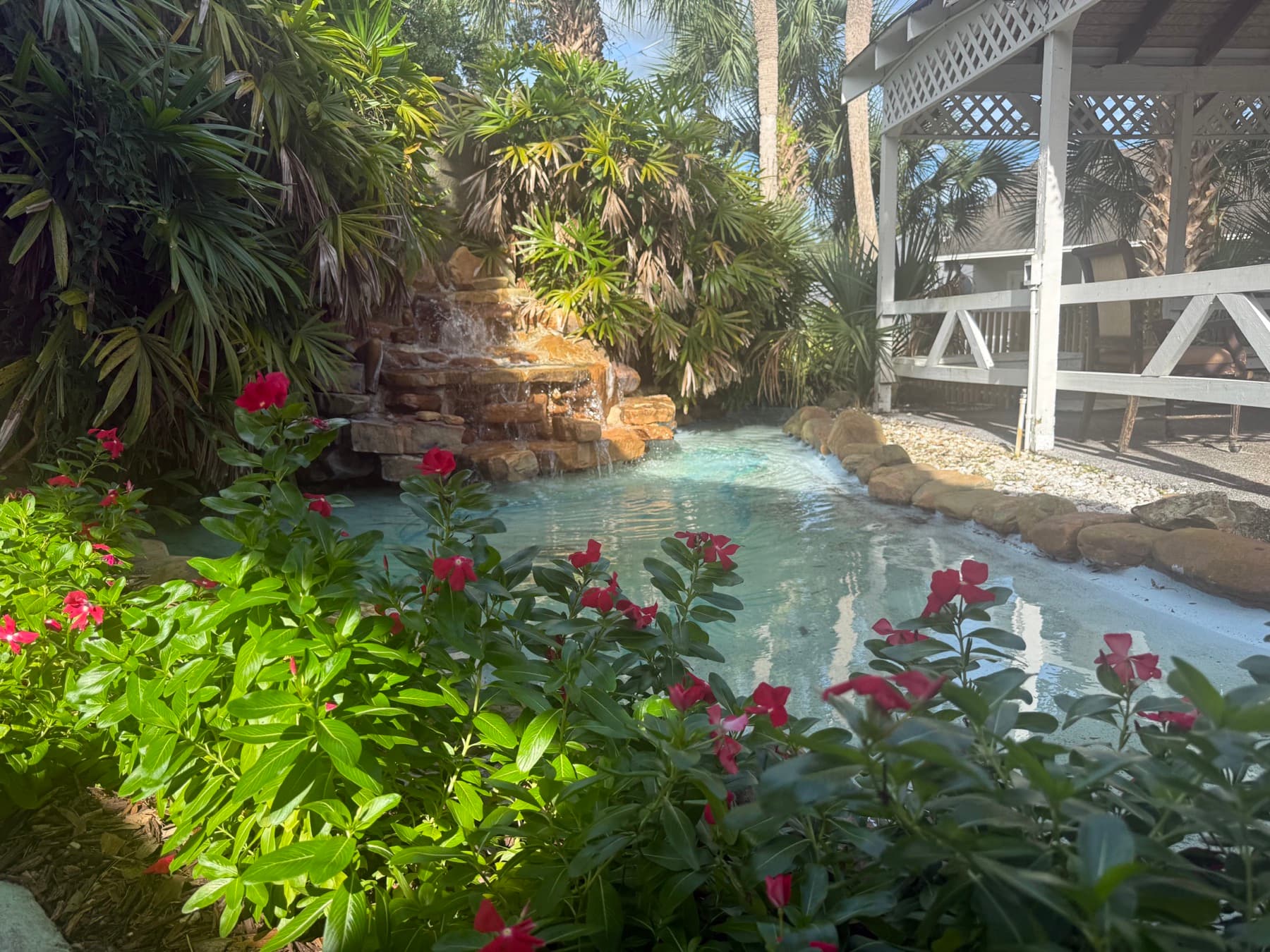 Garden waterfall and pond with flowering plants beside the gazebo